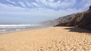 Una playa con cielo despejado y un acantilado rocoso.