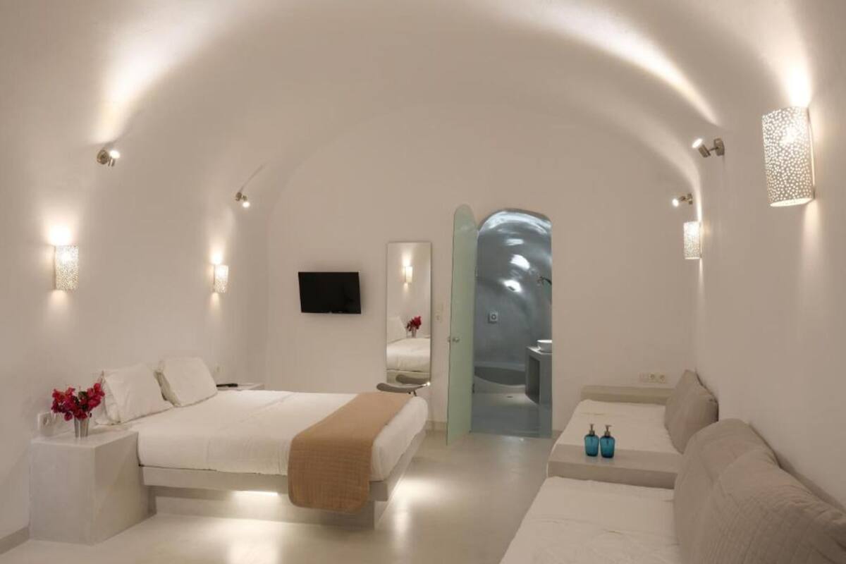 A modern, minimalist bedroom with a large bed, a sofa, and a small table.