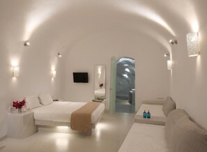 Ein modernes, minimalistisches Schlafzimmer mit einem großen Bett, einer Couch und einem kleinen Tisch.