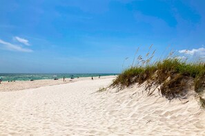 A sandy beach with dunes and a clear blue sky.