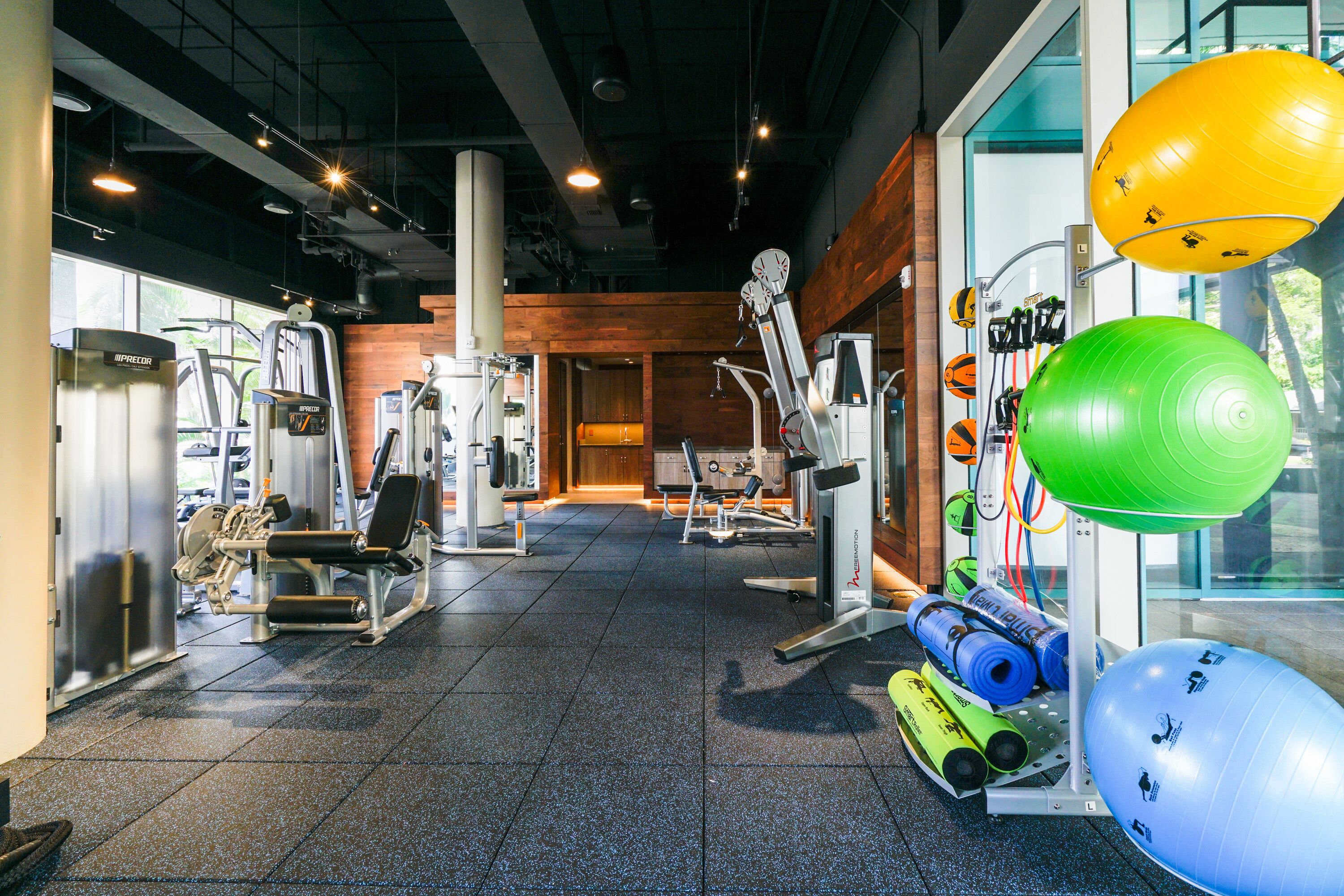 A gym with various exercise equipment, including treadmills, weight machines, and exercise balls.