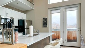 Uma cozinha moderna com uma ilha central, banquetas, micro-ondas e geladeira.