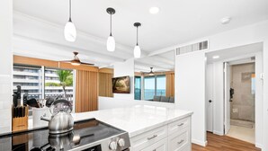 Una cocina moderna con una isla grande, electrodomésticos de acero inoxidable e iluminación colgante.