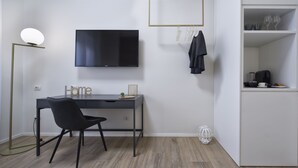 A modern room with a desk, chair, TV, and a coffee machine.
