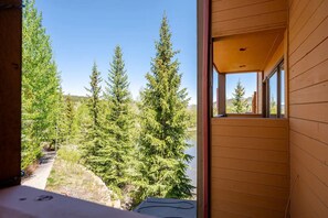 Une cabane en bois offrant une vue sur une forêt dense de conifères et un ciel dégagé.