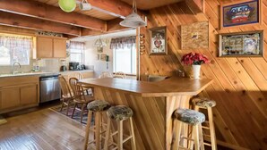 L’intérieur d’un chalet en bois comprend une cuisine, un coin repas et un bar.