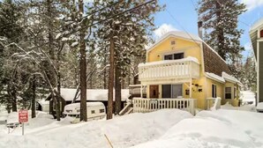 Un bâtiment jaune doté d’un balcon, entouré d’arbres couverts de neige et d’un sol enneigé.