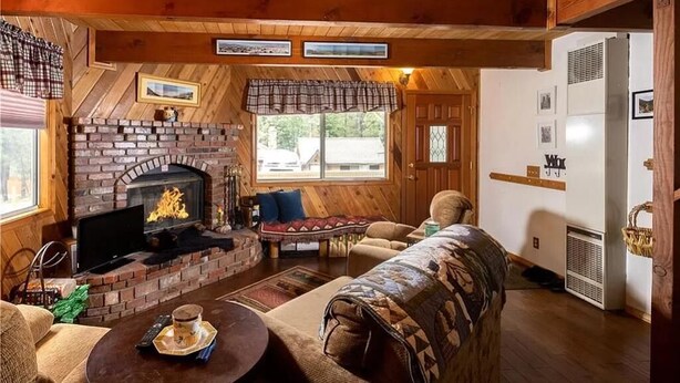 Un intérieur de chalet chaleureux avec une cheminée en briques, un plafond en bois et un coin salon confortable.