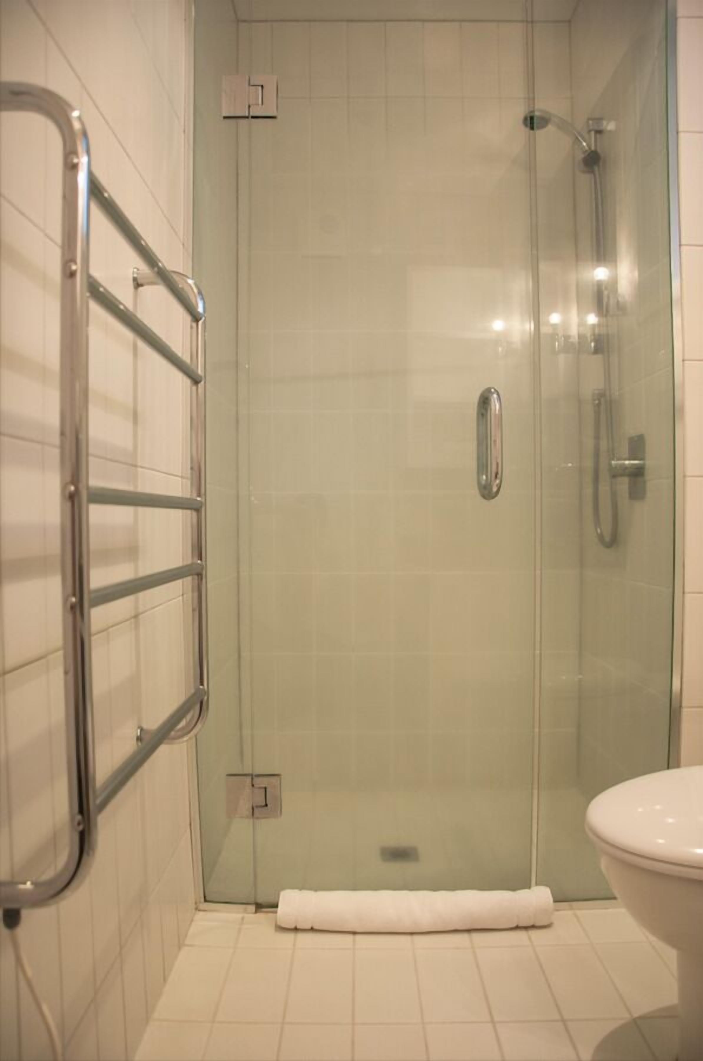 A glass-enclosed shower with a handheld showerhead and a glass door.