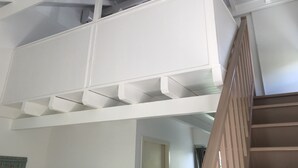 A white interior with a wooden staircase leading to a mezzanine level. - Kaymargo, Creole bungalow (Saint-Esprit)