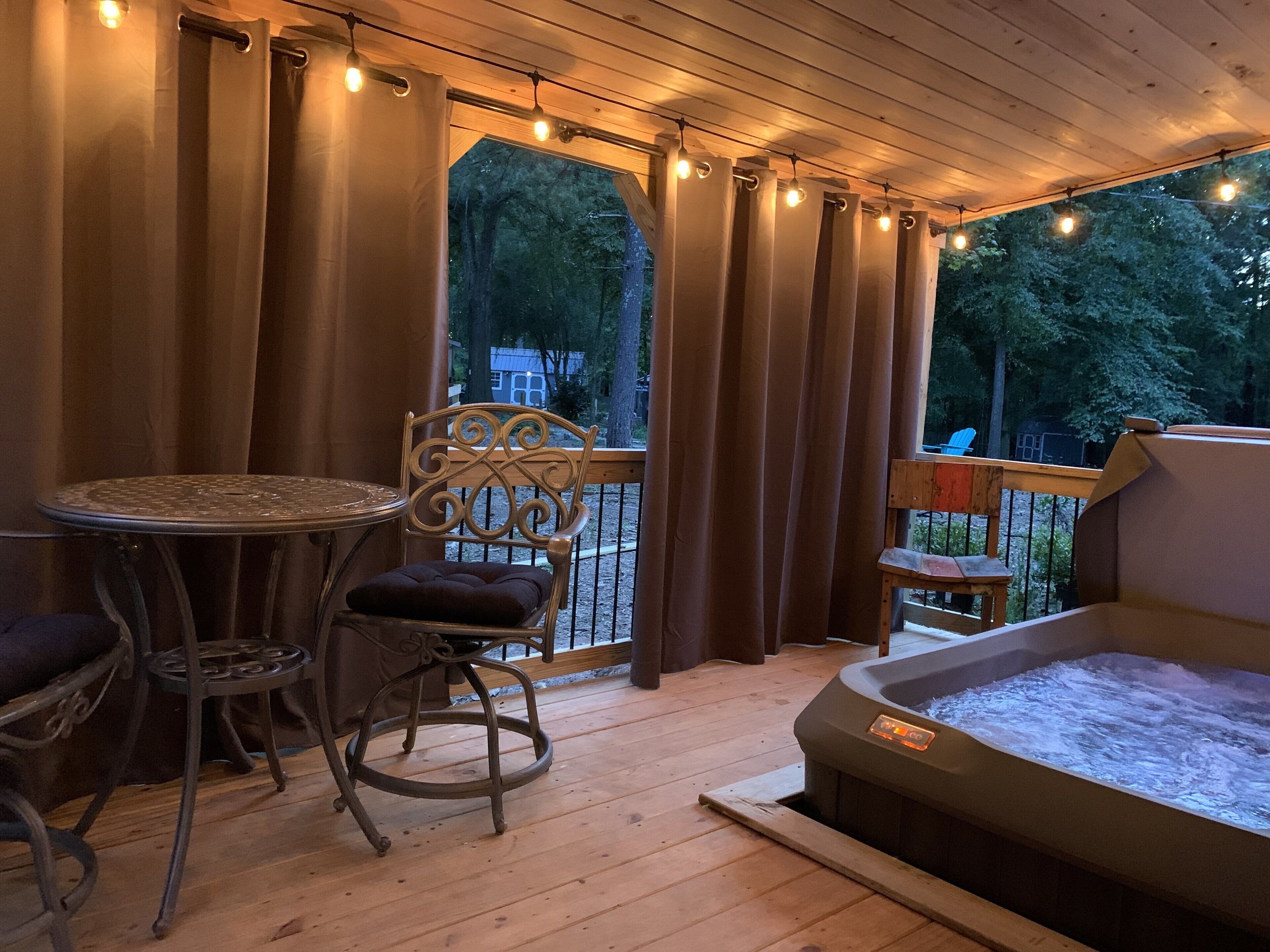 Une terrasse en bois avec un jacuzzi, une table et deux chaises.