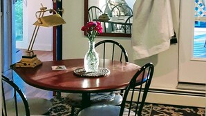 A dining area with a wooden table, four chairs, a vase with flowers, and a lamp. - Panoramic view, large deck, ground floor apartment, walk to subway and beach (Boston)