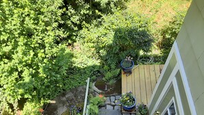 A garden with a stone pathway, potted plants, and a wooden deck. - Panoramic view, large deck, ground floor apartment, walk to subway and beach (Boston)