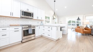 Une cuisine moderne avec des meubles blancs, des appareils en acier inoxydable et un plan de travail en bois.