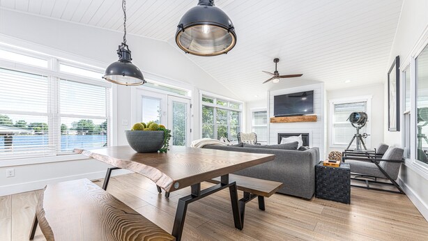 Une cuisine moderne avec une table et un banc en bois, un canapé gris et un ventilateur de plafond.