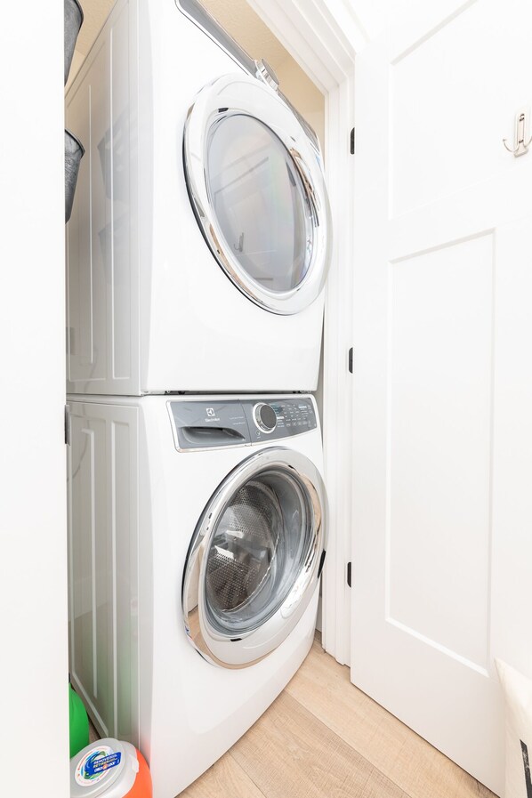 Een kleine, witte wasruimte met twee deuren, met een ingebouwde wasmachine en droger.