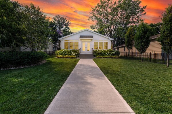 A single-story house with a front entrance, a concrete pathway leading to the door, and a well-maintained lawn.