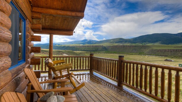 A wooden cabin with a porch, wooden rocking chairs, and a view of a mountainous landscape. - True Montana Log Cabin, Yellowstone Park, Ennis, Madison River Fishing,  4+2.5 (Cameron)