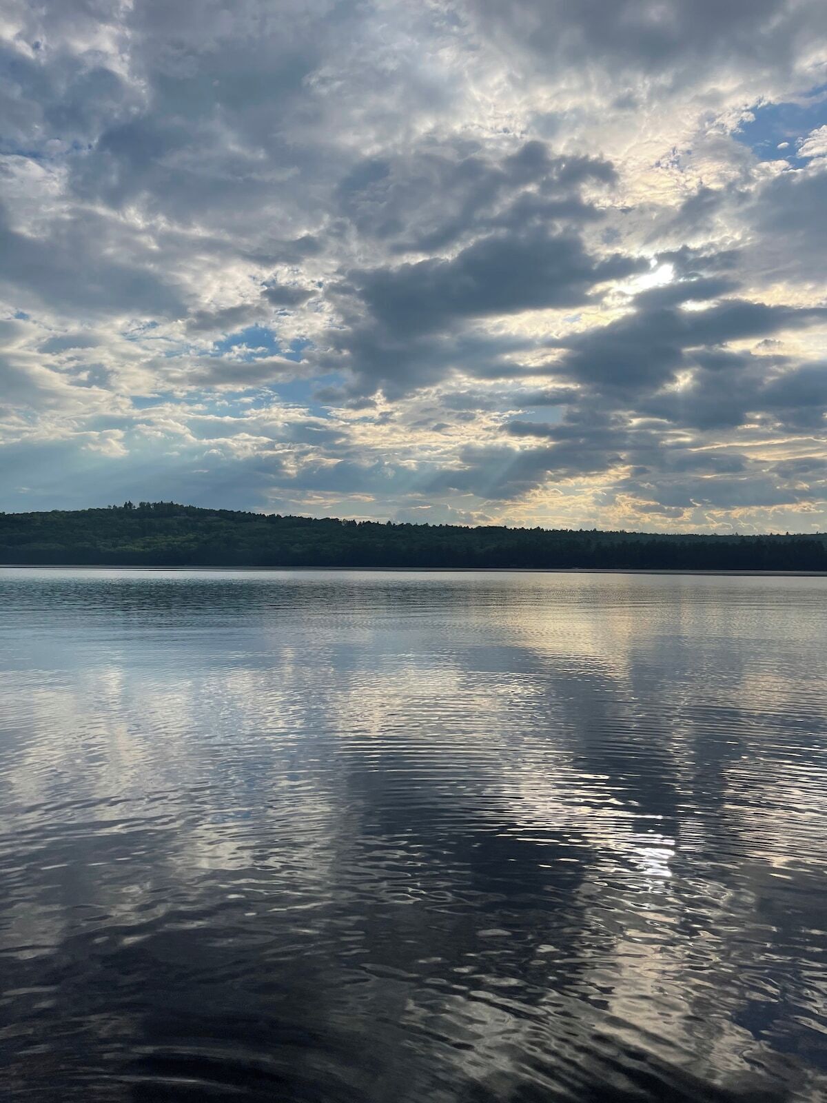 Un lac paisible, avec une colline boisée en arrière-plan.