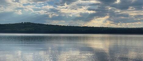 Un lac paisible, avec une colline boisée en arrière-plan.
