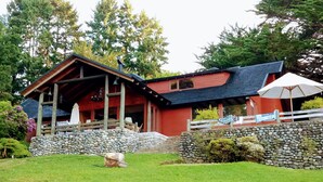 A rustic cabin with a stone foundation, wooden beams, and a red exterior. - Rent house villarrica-pucon (eclipse 2020) (Villarrica)