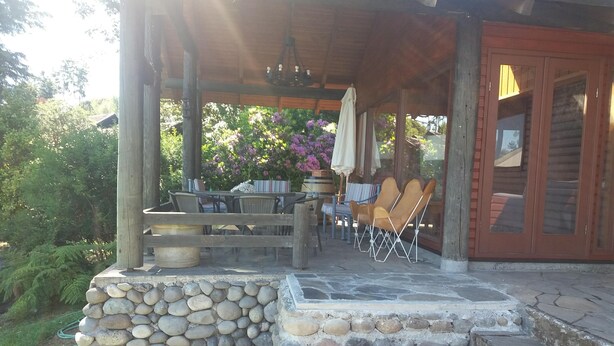 A covered patio area with stone steps leading to a seating area with chairs and a table. - Rent house villarrica-pucon (eclipse 2020) (Villarrica)
