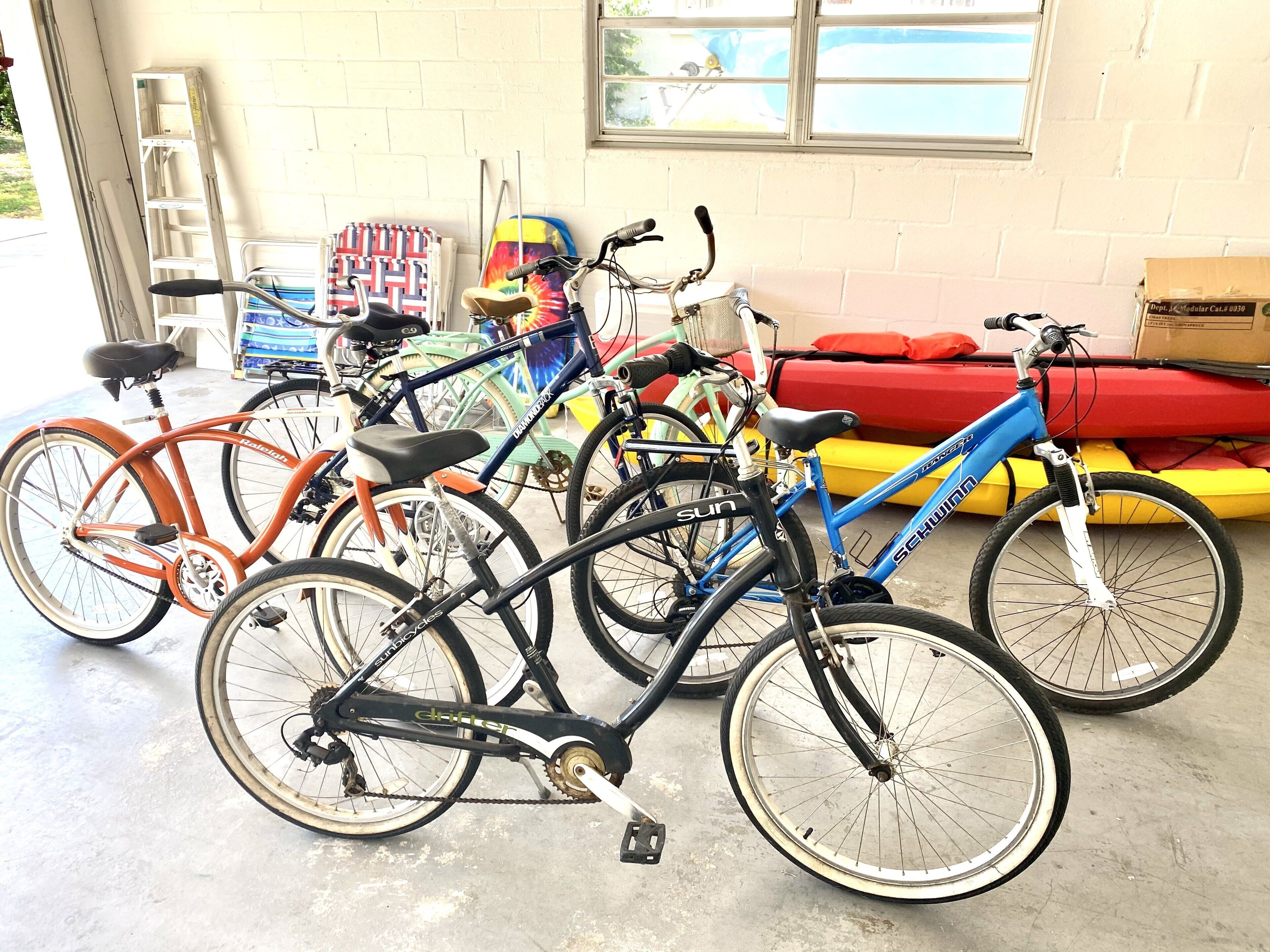 Bicycles parked indoors with a concrete floor and a window in the background.