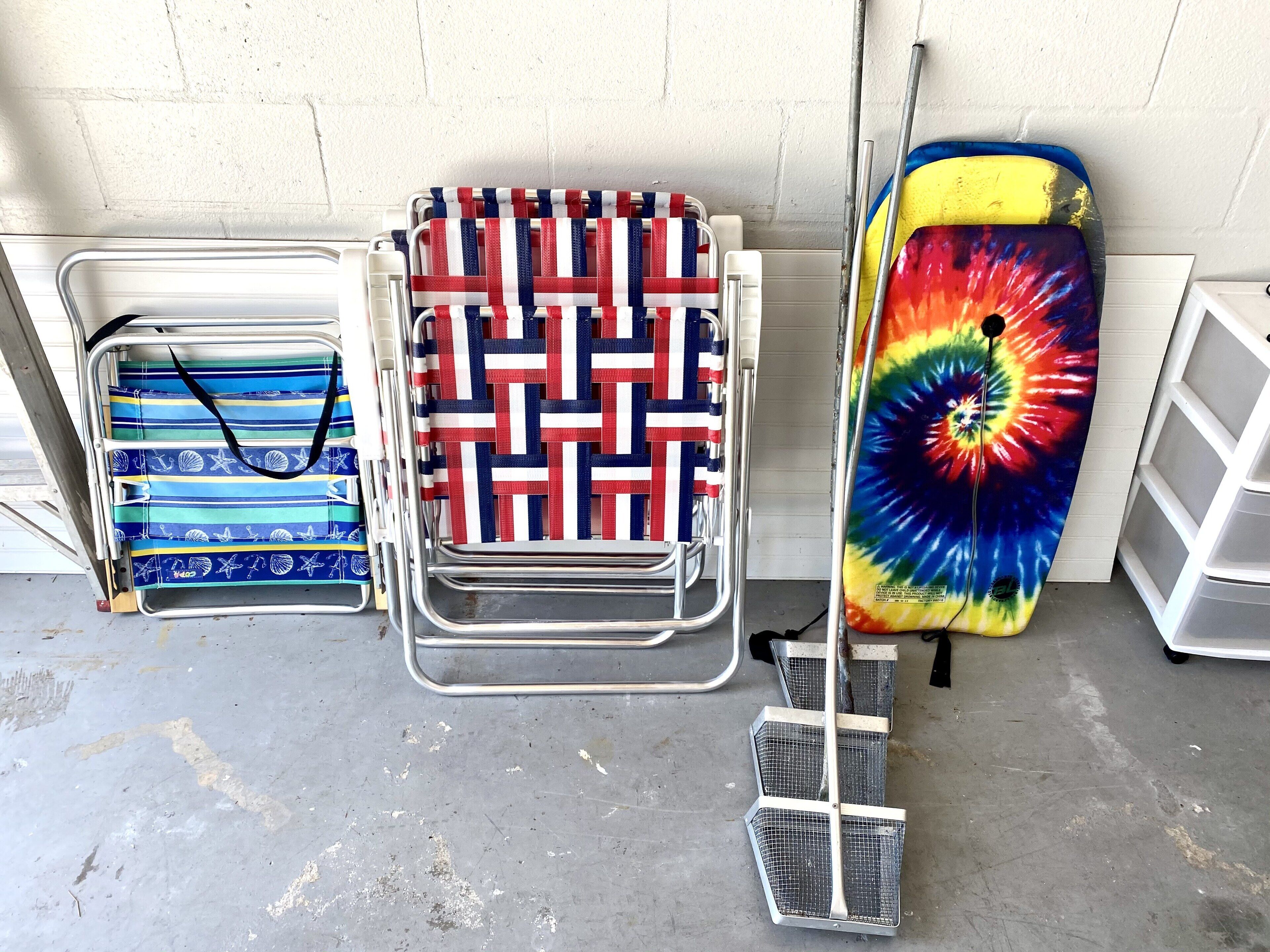 Area di stoccaggio con scaffali metallici che contengono diversi oggetti, tra cui un colorato longboard psichedelico e borse fantasia.