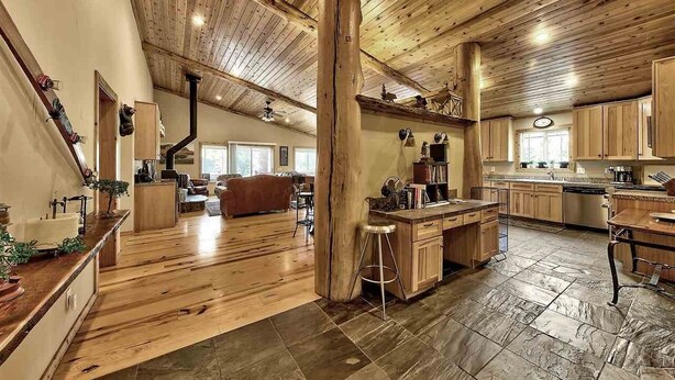 A spacious living area with a wooden ceiling, a kitchen with wooden cabinets, and a dining area with a bar. - Cabin retreat with Hot Tub (Truckee)