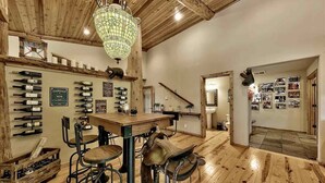 A rustic interior with wooden floors, a bar area with wine bottles, and a hanging light fixture. - Cabin retreat with Hot Tub (Truckee)