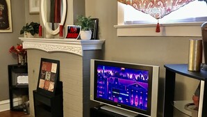 Een woonkamer met een open haard, een televisie en een raam met behang.