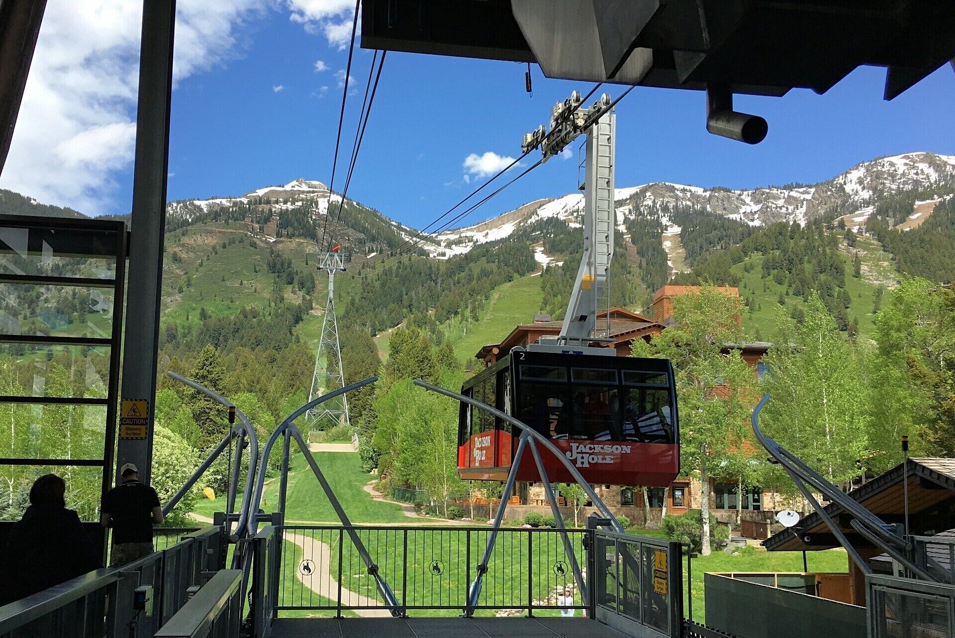 A cable car station with a view of snow-capped mountains and a green valley.