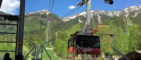 A cable car station with a view of snow-capped mountains and a green valley.