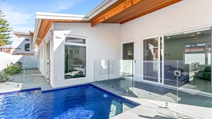 A modern house with a swimming pool, large glass doors, and a wooden ceiling.