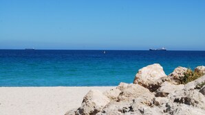 A beach with rocky foreground and calm sea.