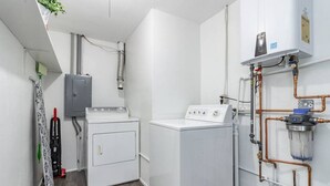 Un cuarto de lavado con lavadora, secadora y calentador de agua.