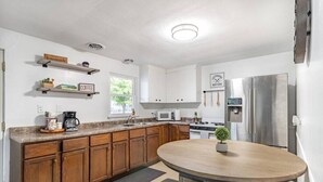Una cocina moderna con armarios de madera, encimera de granito, una mesa redonda para comer y un horno empotrado.