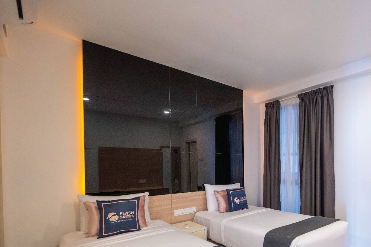 A hotel room with two beds, a large mirror, a shower area, and a view of the city.