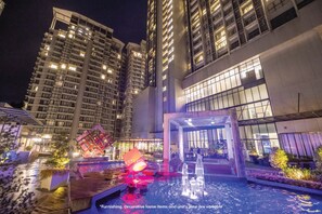 Un hotel moderno con zona de piscina en la azotea, que incluye una fuente y asientos.