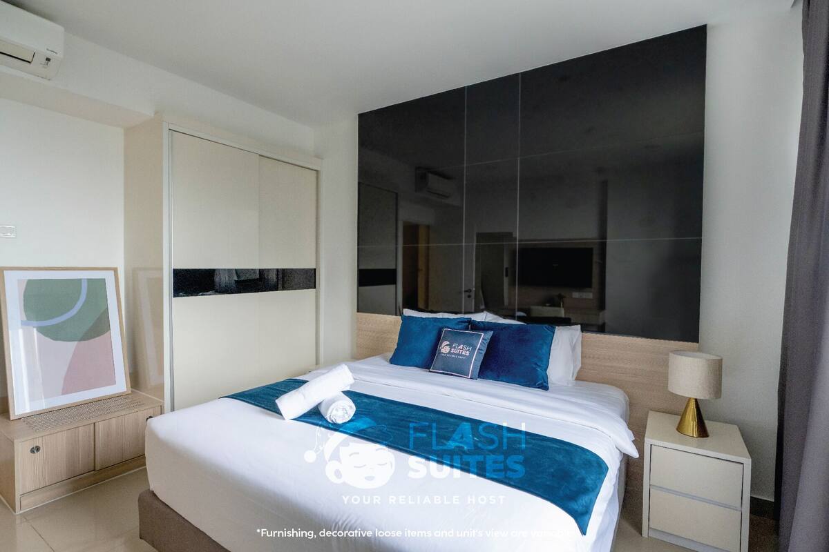 A modern hotel room with a large bed, a nightstand, a wall-mounted air conditioner, and a framed picture on the left side.
