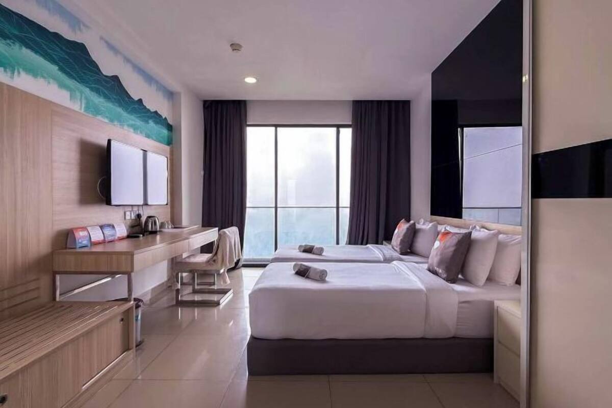 A hotel room with a bed, a desk, a chair, a TV, and a window.