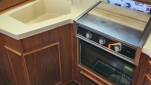 Cozinha compacta com armários de madeira, fogão de aço inoxidável e uma pia.