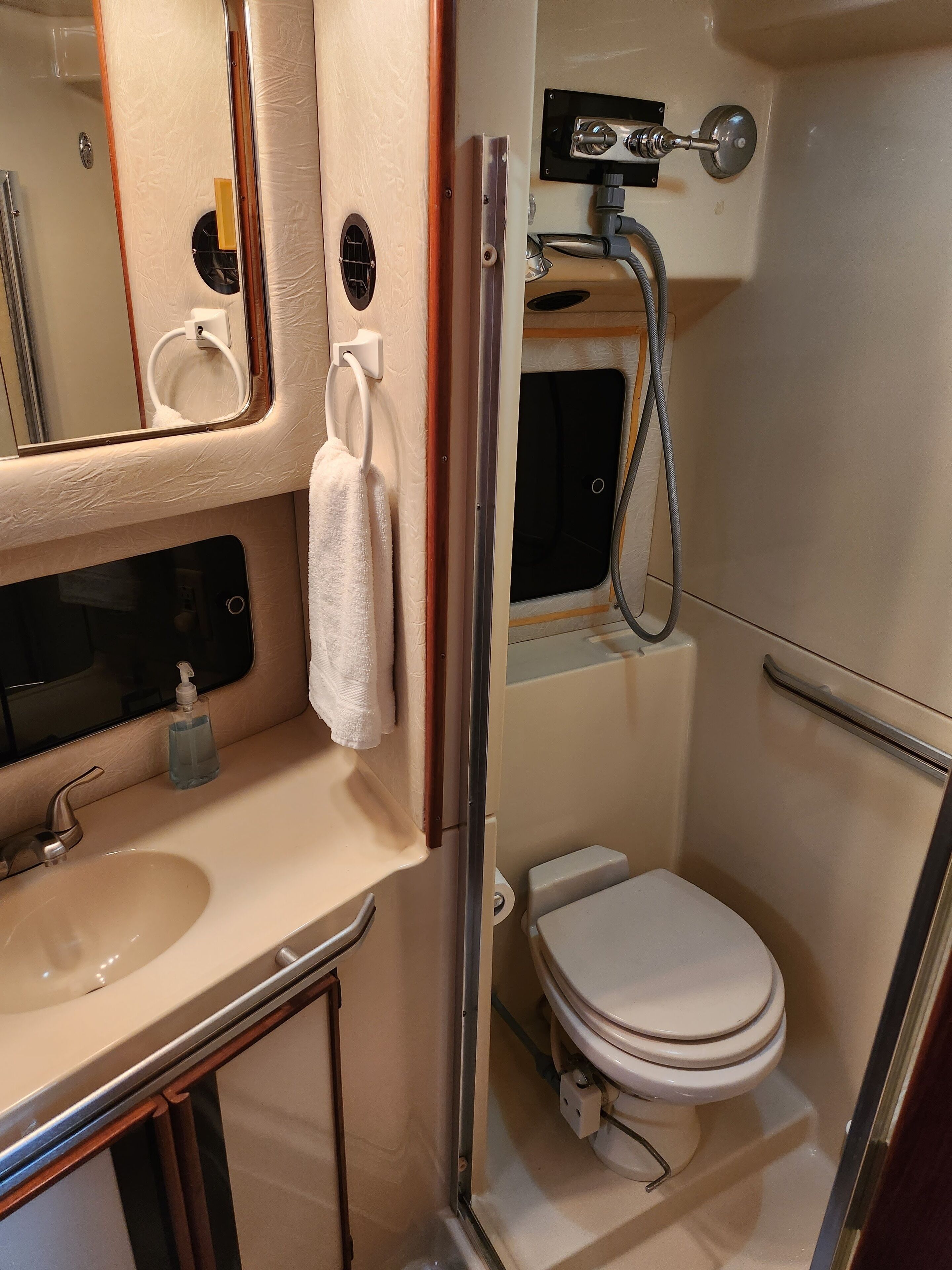 Baño pequeño con lavamanos, espejo, toalla, inodoro y ducha.