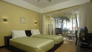 Habitació d'hotel amb dos llits, televisió i un balcó amb vista a palmeres.