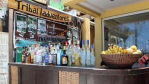 Zona de bar amb un cartell que diu "Tribal Adventures" i una presentació de diverses ampolles.