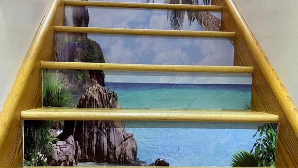 Una escalera de madera con un mural tropical.