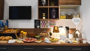 Una cocina con un televisor de pantalla plana, armarios de madera y una variedad de alimentos en la encimera.