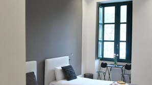 Un dormitorio moderno con dos camas, una mesita, sillas y una ventana con vistas.