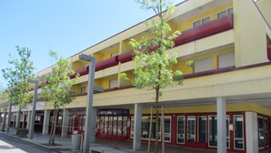 A multi-story building with a yellow facade, large windows, and a red awning. - Colorful Studio by the Beach-beahost (San Michele al Tagliamento)