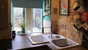 A kitchen with a large window, a sink, and various kitchen utensils on the wall.